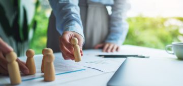A group of business team brainstorming and planning strategy together with wooden people in a meeting